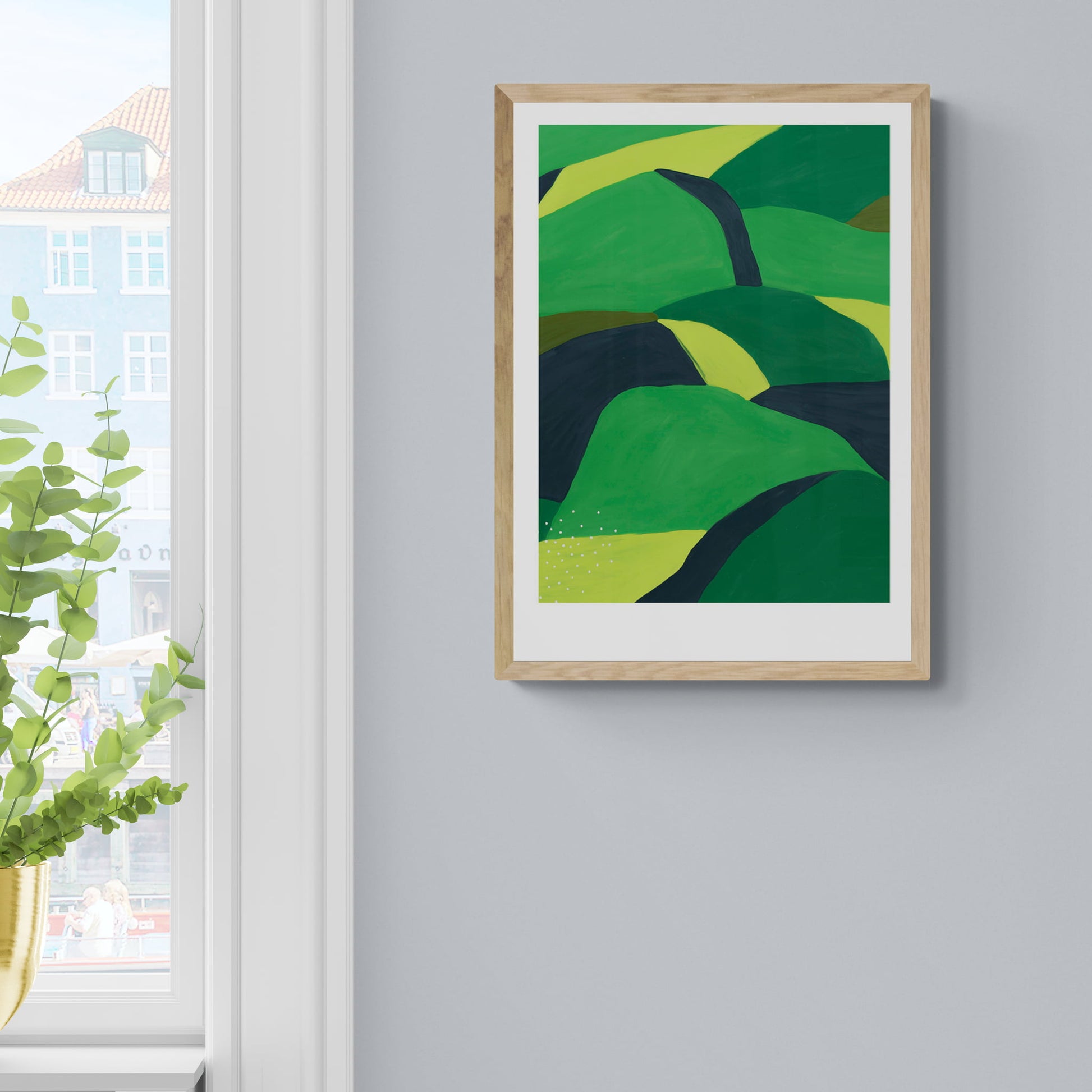 Framed landscape of greens and black rolling hills hanging om wall.