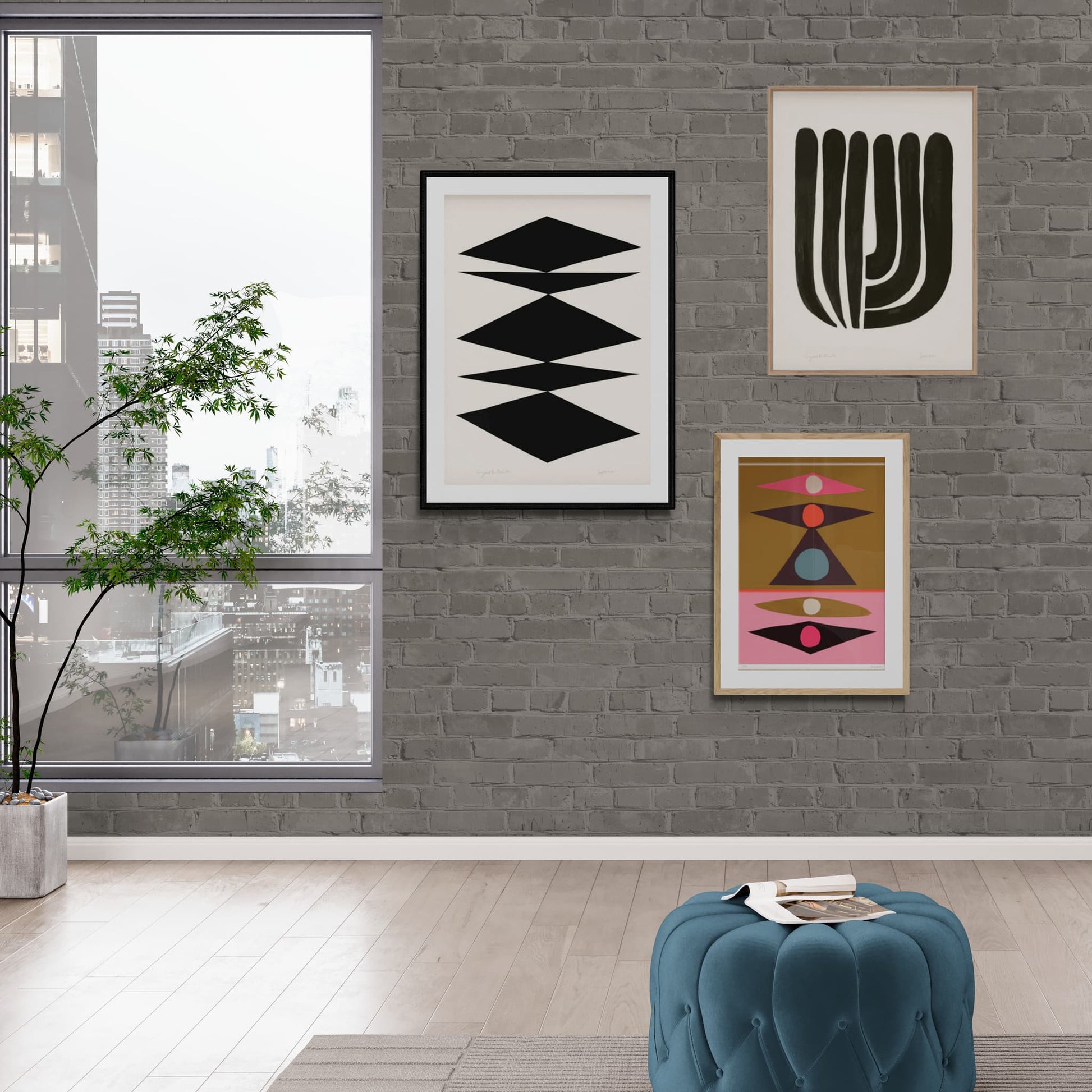 Grouping of three prints framed and hanging on a brick apartment wall, 2 monochrome and a multi coloured geometric print