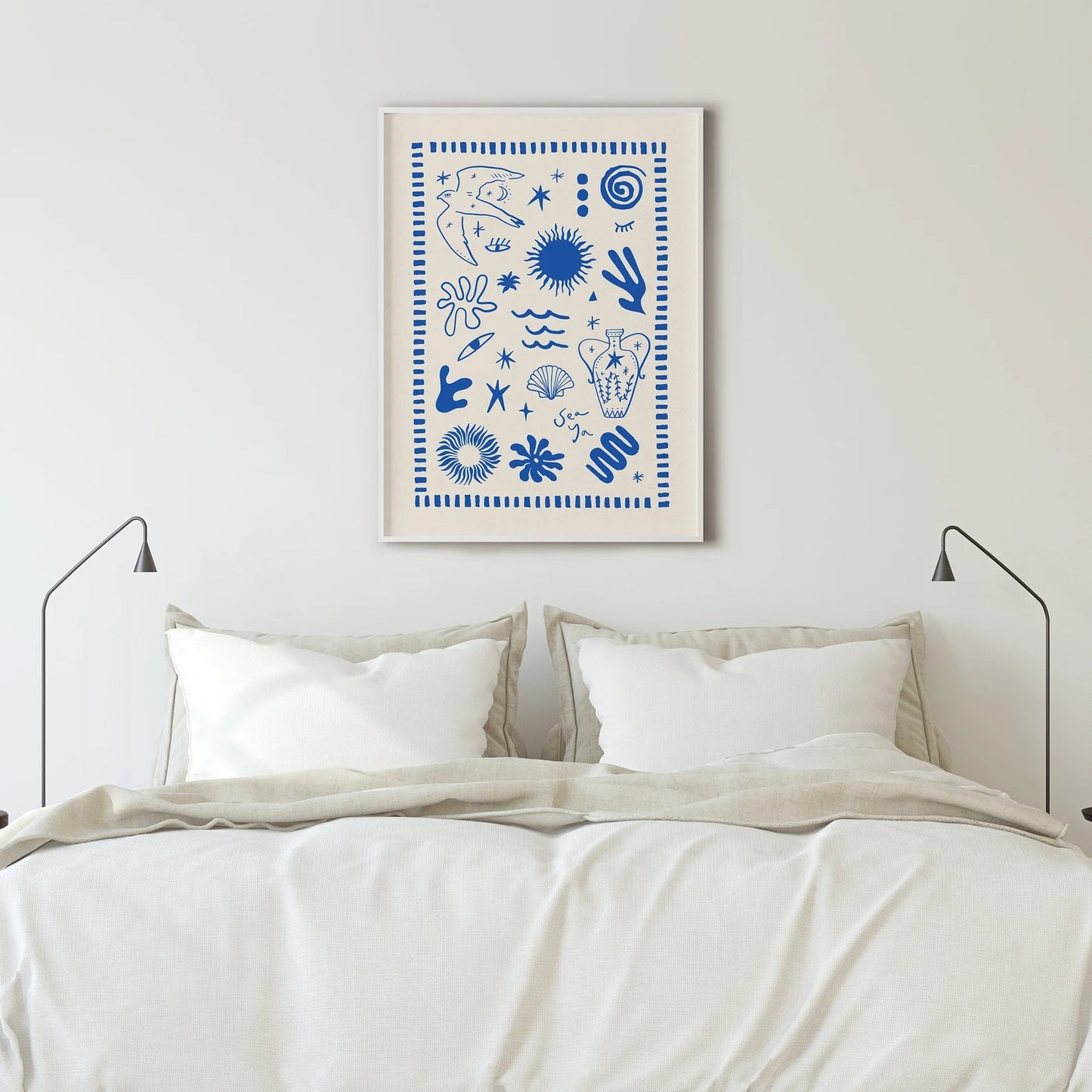 Framed blue and white Solstice Studio Greece print on white wall above a bed