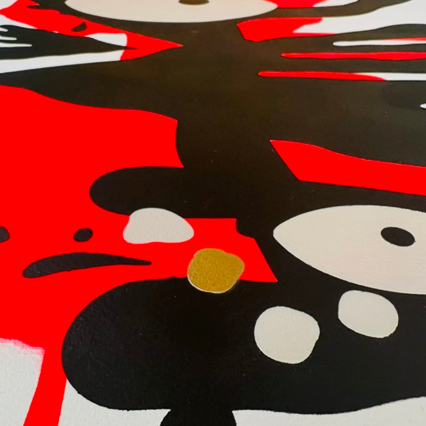 Close up of abstract painting of red and black with eye and gold dot accents