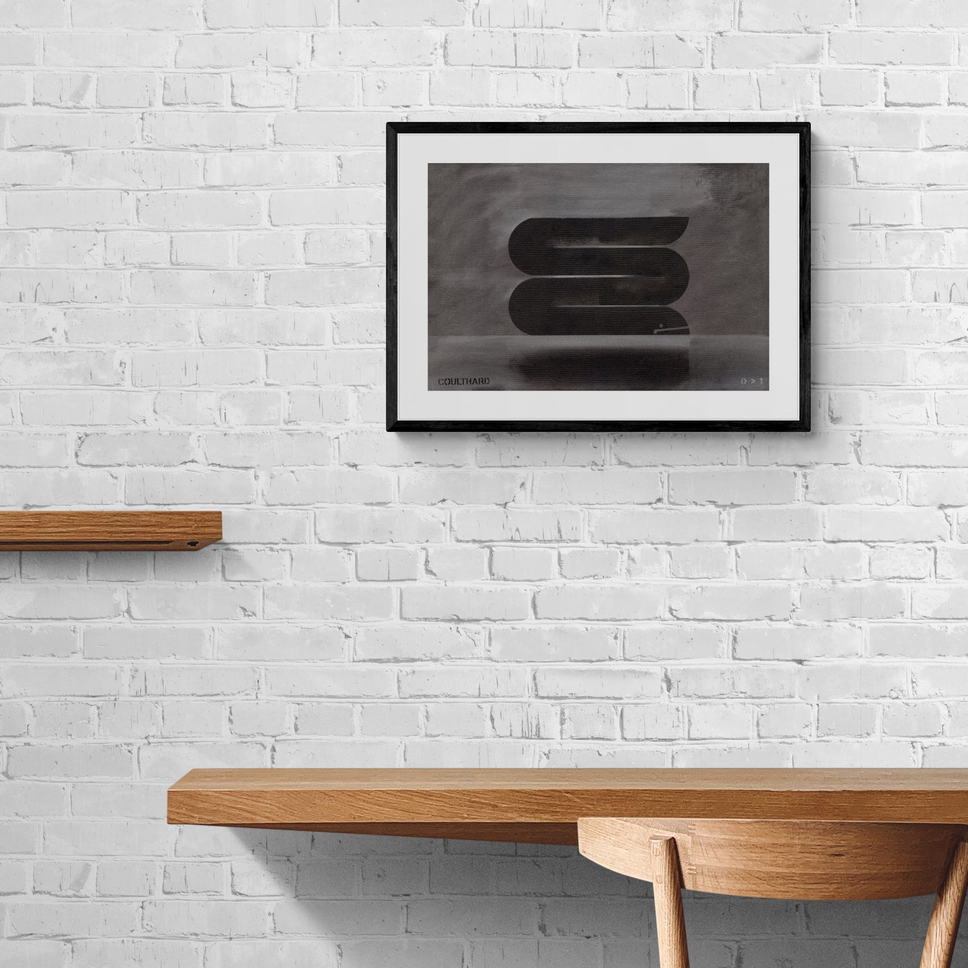 Framed black and grey print of an eel hanging on brick wall.