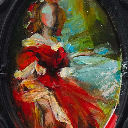 Close-up of a decorative black frame with a colourful painting by Anita DeSoto, of a woman in a red dress on a white background