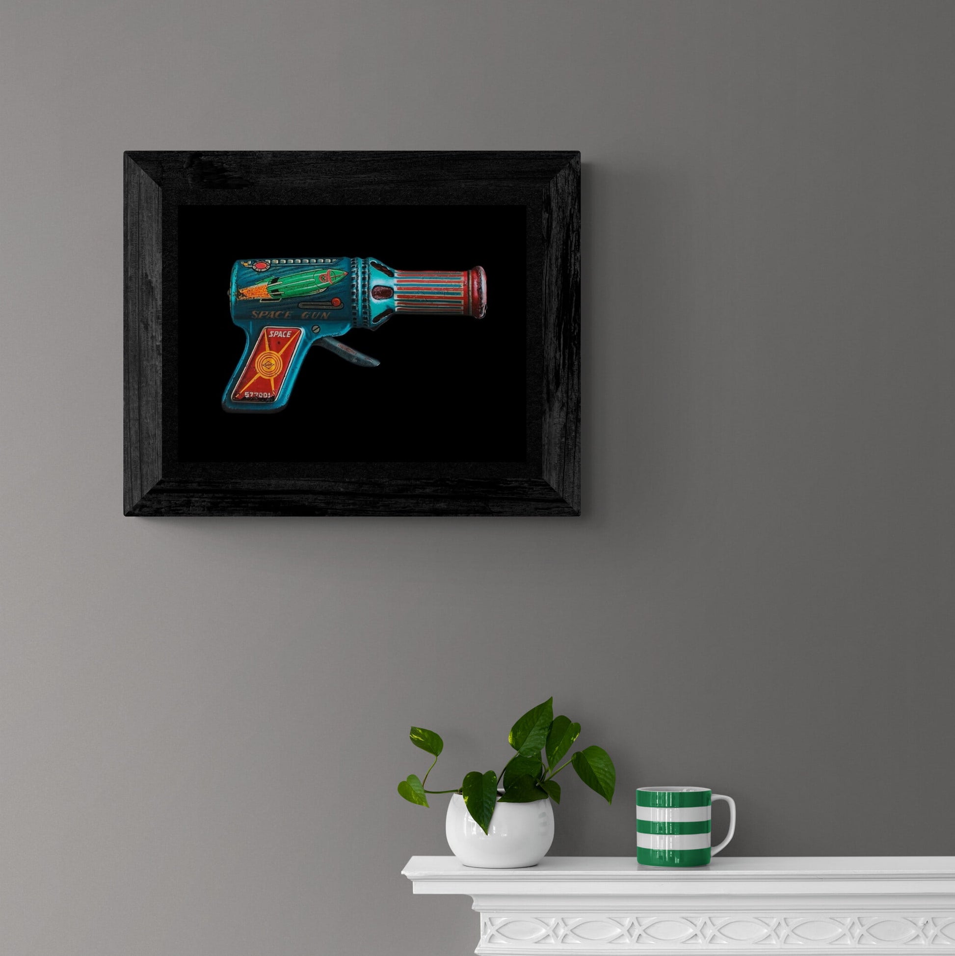 Framed and hanging old school image of lead toy raygun.