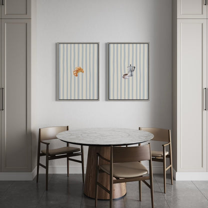 Two framed vertical art prints by Solstice Studio Prints, hanging above a dining table and chairs. The prints have pale blue and cream stripes with small decorative illustrations.