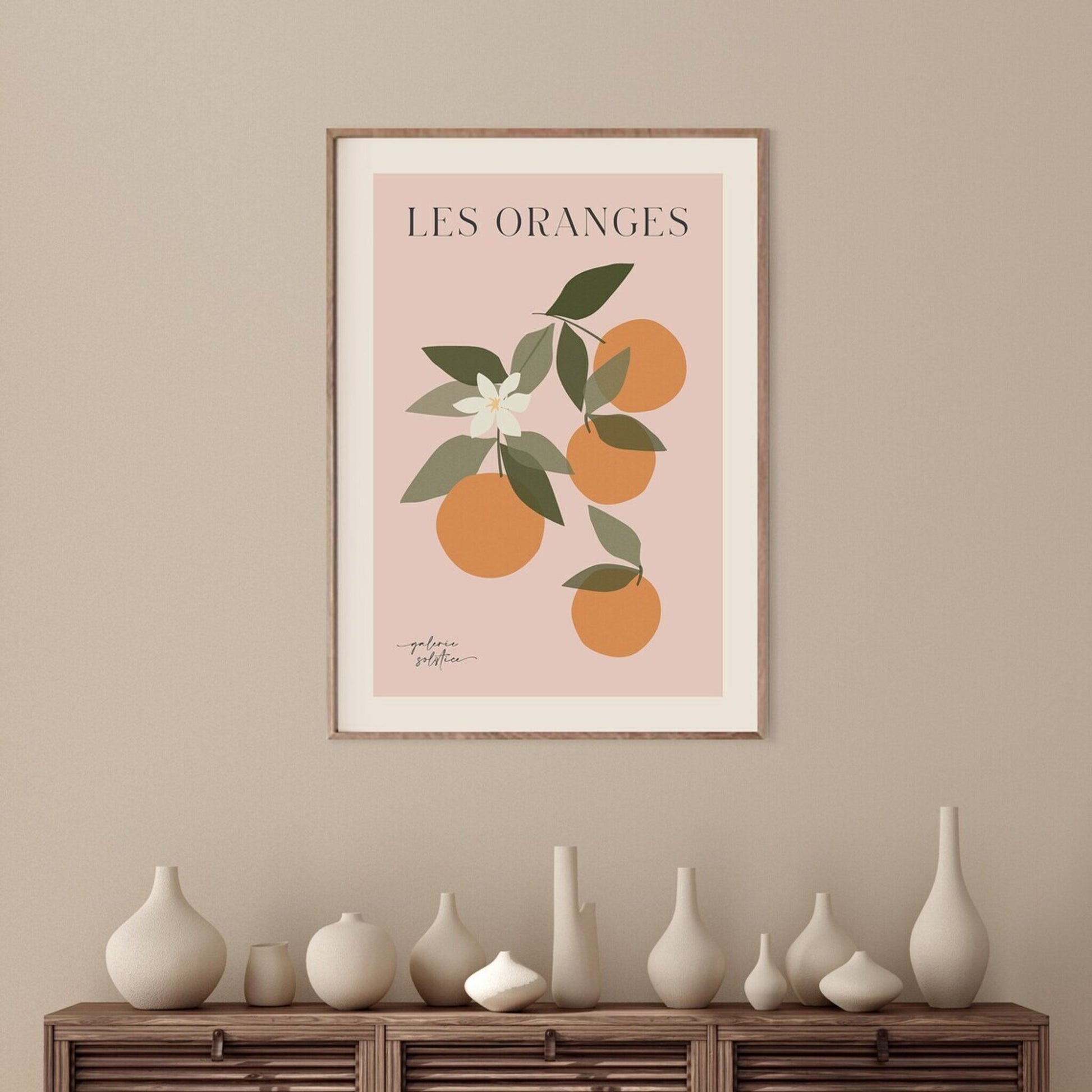 Framed print of oranges, green leaves and blossom hanging on wall.