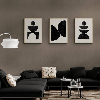 Group of three framed black abstract prints hanging above contemporary couch