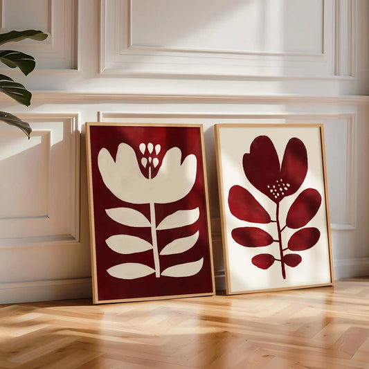 Two framed floral and leaf prints on a wooden floor with a neutral wall background
