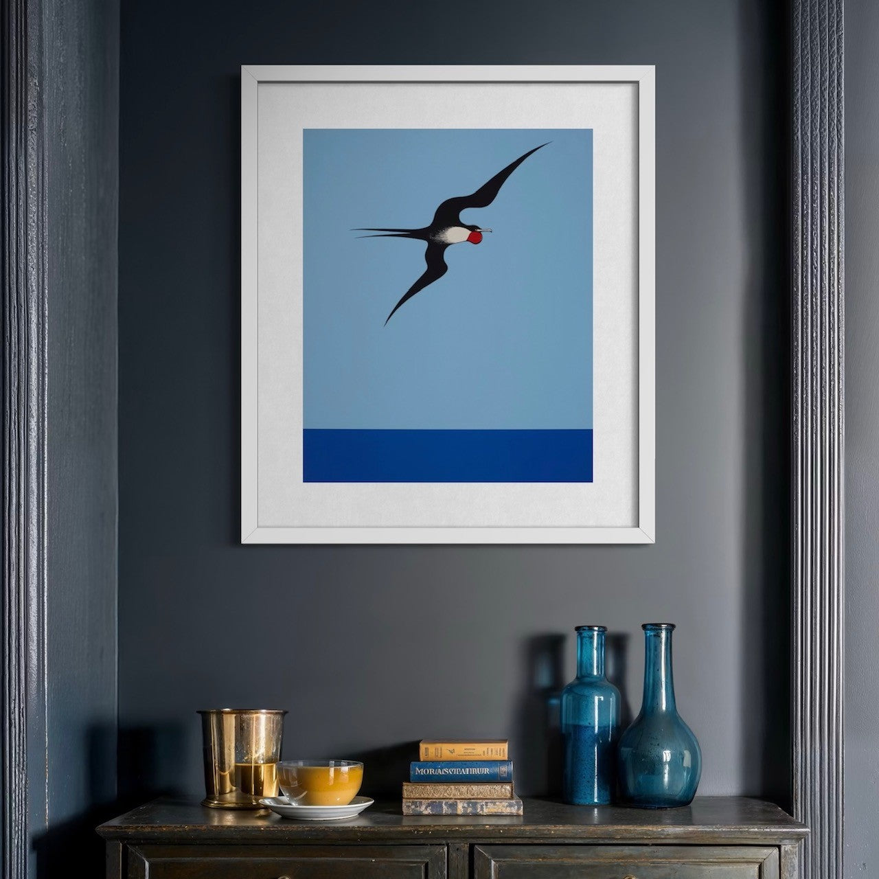 Framed and hanging Frigate Bird reproduction print by Don Binney featuring a bold bird silhouette against a dramatic sky.