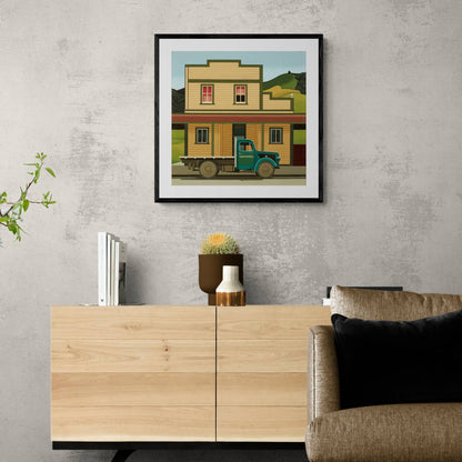 Framed and hanging print of old wooden building and green truck.