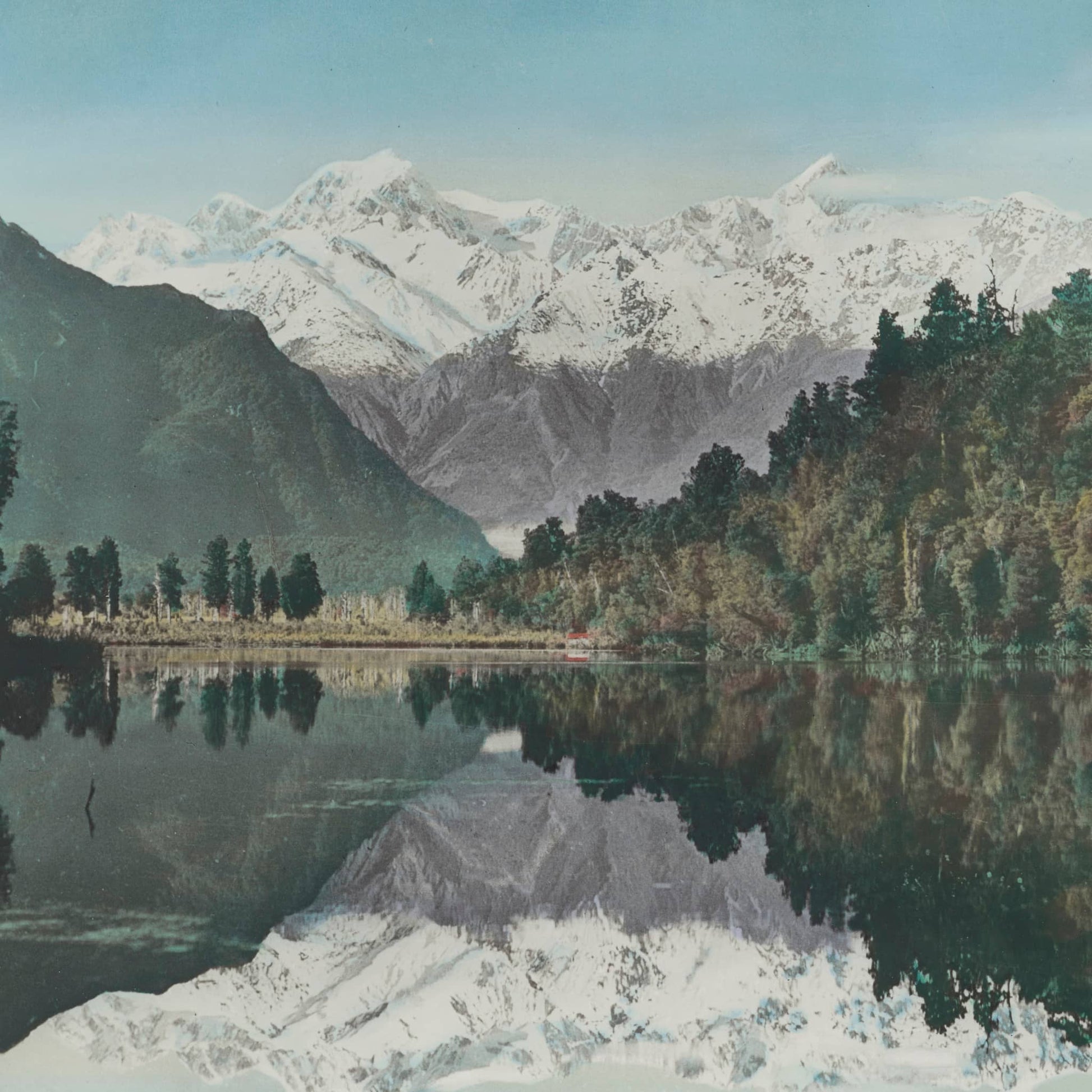 Print of lake with mountains, sky and bush mirrored in it.