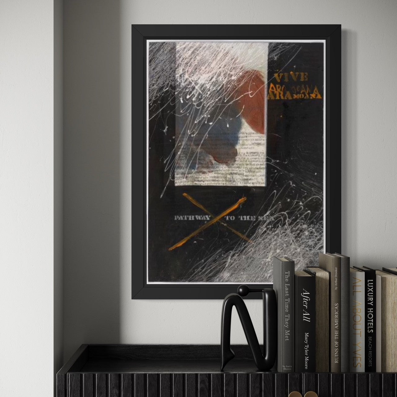 Framed abstract artwork on a wall with books below