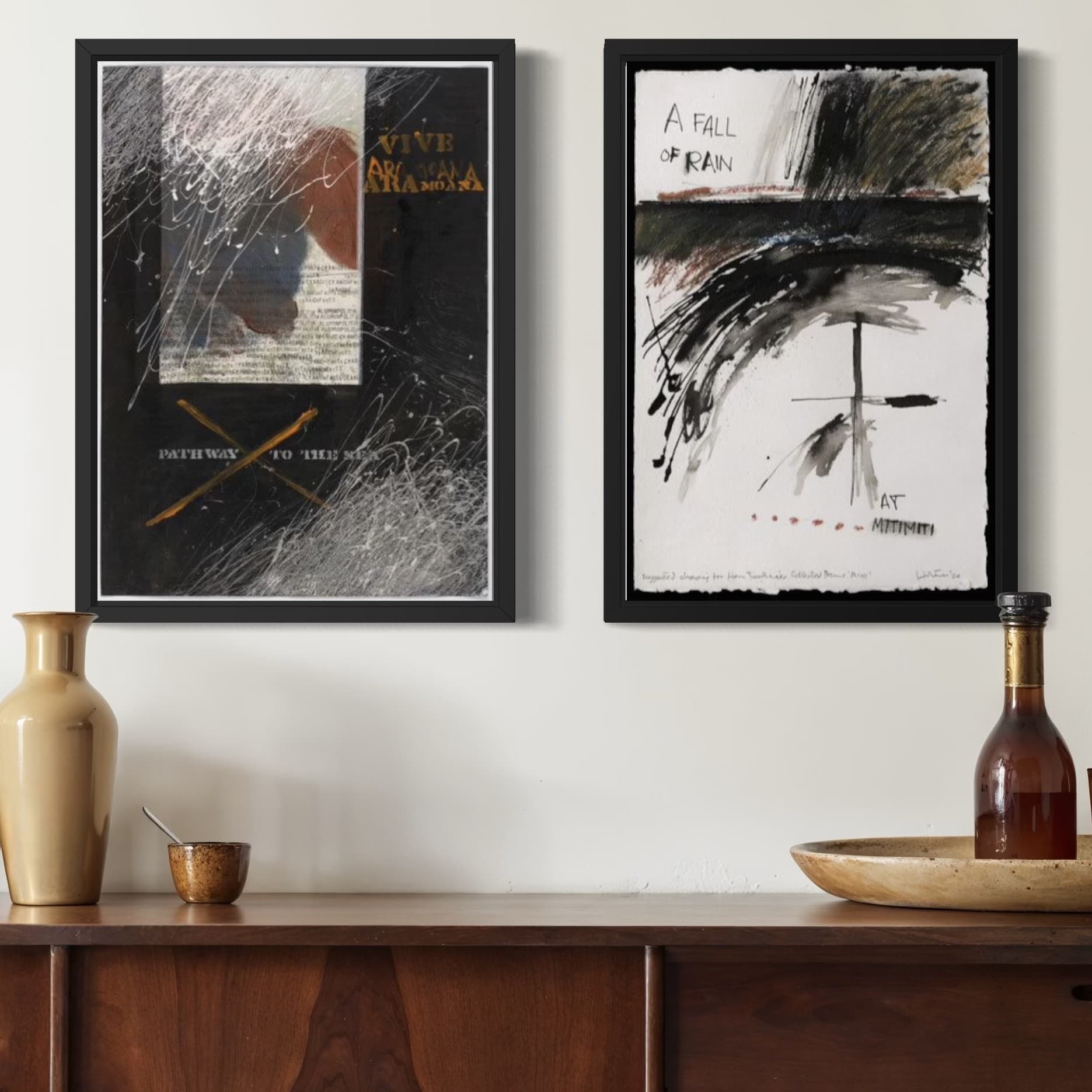 Two abstract Ralph Hotere artworks on a wall above a wooden cabinet with decorative items.