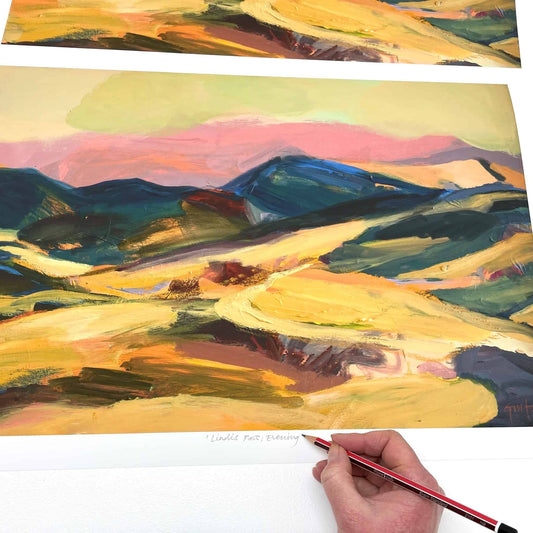 Colourful evening landscape print in yellow and gold with blue hills and pink sky.