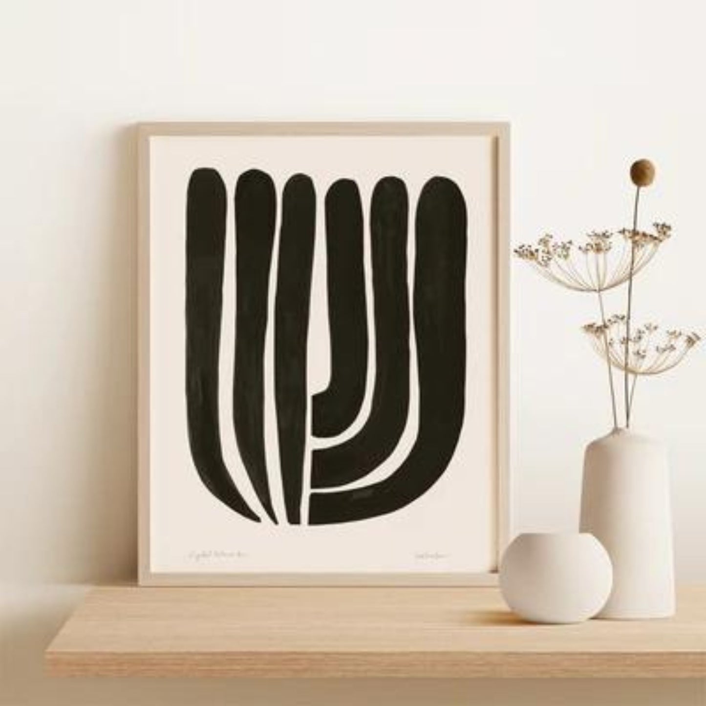 Framed back and white tulip shaped abstract print. leaning on shelf.